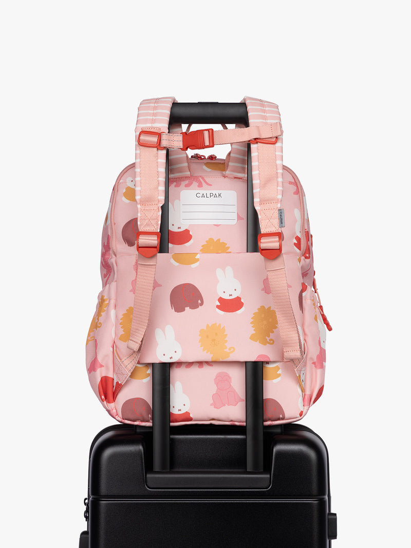 Back luggage trolley sleeve of Side view of CALPAK Kids Large Backpack with Miffy and pink colorful animal pattern on a white background