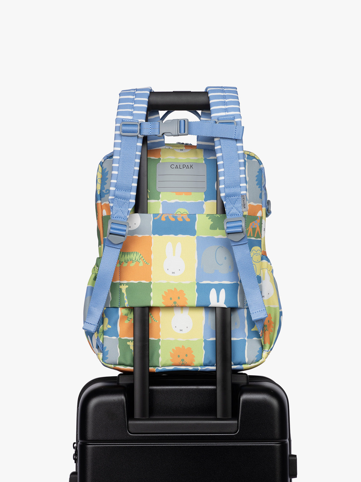 Back luggage trolley sleeve of  CALPAK Kids Medium Backpack with Miffy and blue colorful animal pattern on a white background; CKBM2501-MIFFY-BLUE-ZOO-TRIP