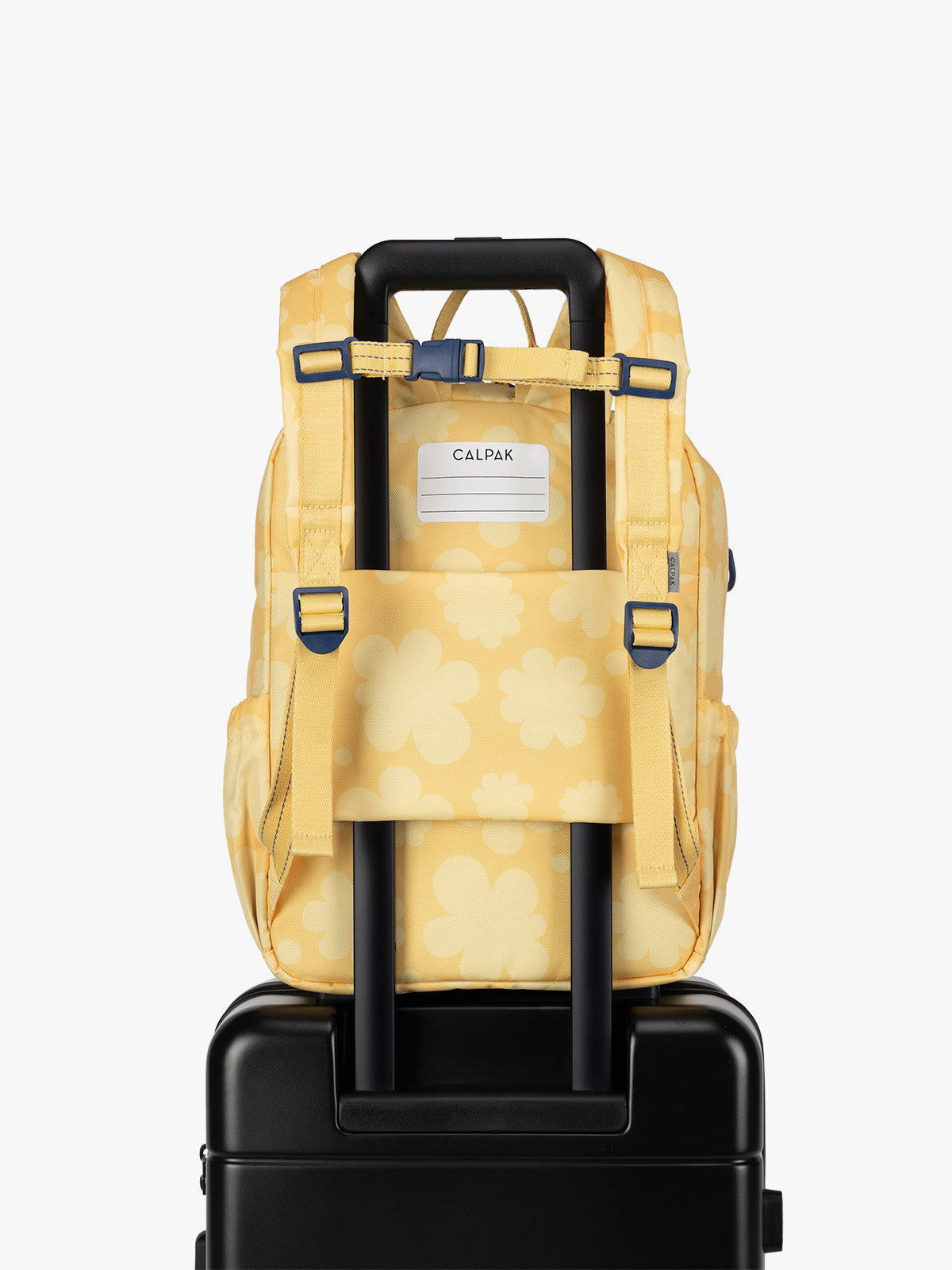 CALPAK Kids Medium Backpack in yellow with tan flower print in Yellow Bloom for ages 5-8 with back luggage trolley sleeve; CKBM2501-YELLOW-BLOOM