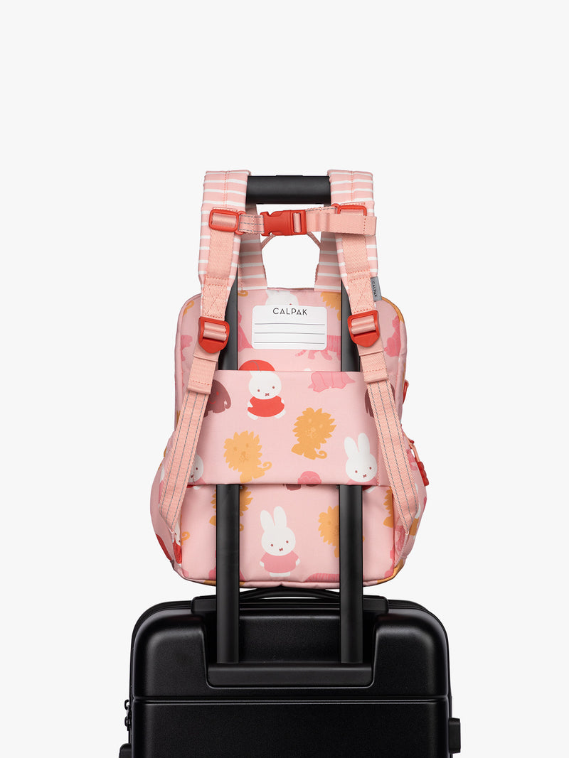 Back luggage trolley sleeve of CALPAK Kids Small Backpack with Miffy and pink colorful animal pattern on a white background