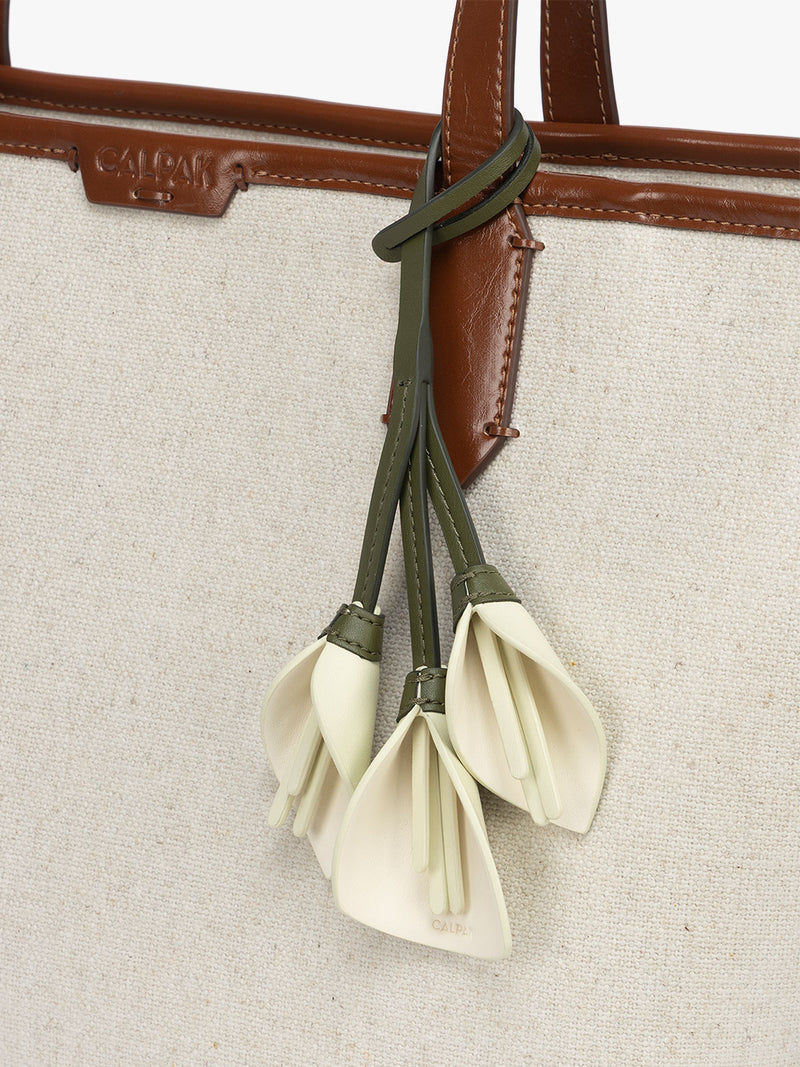 CALPAK Colette Calla Lilly Bag Charm with dark green strap and Celadon flower stem and white flower petals attached to a bag