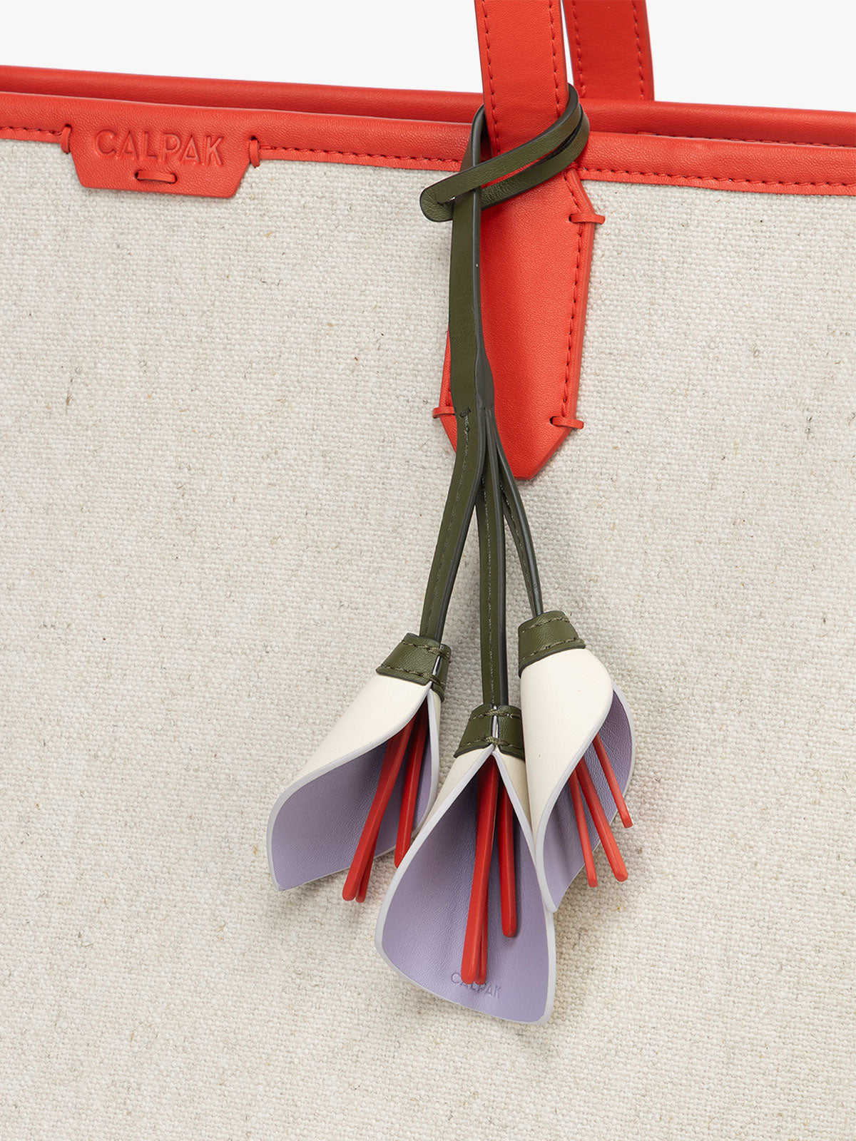 CALPAK Colette Calla Lilly Bag Charm with dark green strap and Red tomato flower stem attached to bag with white and purple petals; CLBC2601-LAVENDER