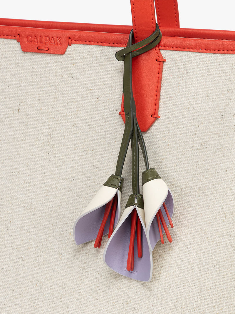 CALPAK Colette Calla Lilly Bag Charm with dark green strap and Red tomato flower stem attached to bag with white and purple petals