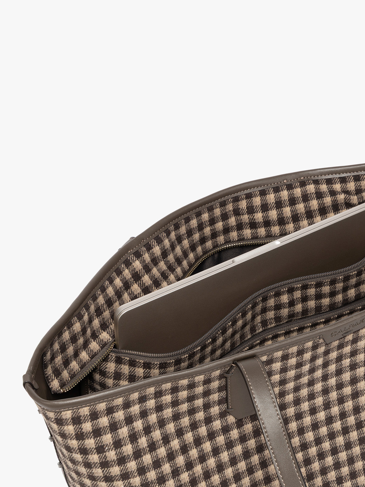 Close-up of Colette 15 Laptop Tote bag with a brown and beige gingham pattern and dark brown leather handles in Mushroom interior showing a brown and beige checkered pattern lining, a zippered pocket holding a silver laptop, and dark brown leather trim against a light gray background; CLCT2601-MUSHROOM-PLAID