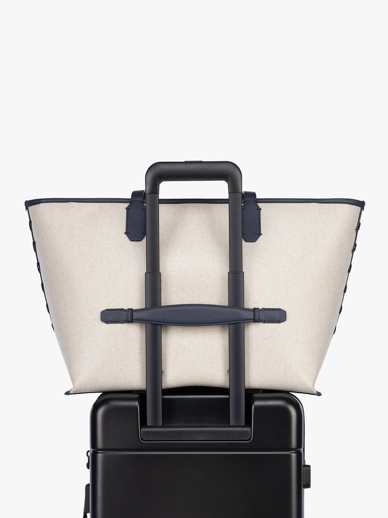 Trolley sleeve of CALPAK Colette 15" Canvas Laptop Tote in beige canvas material  with blue finishing in Natural Navy