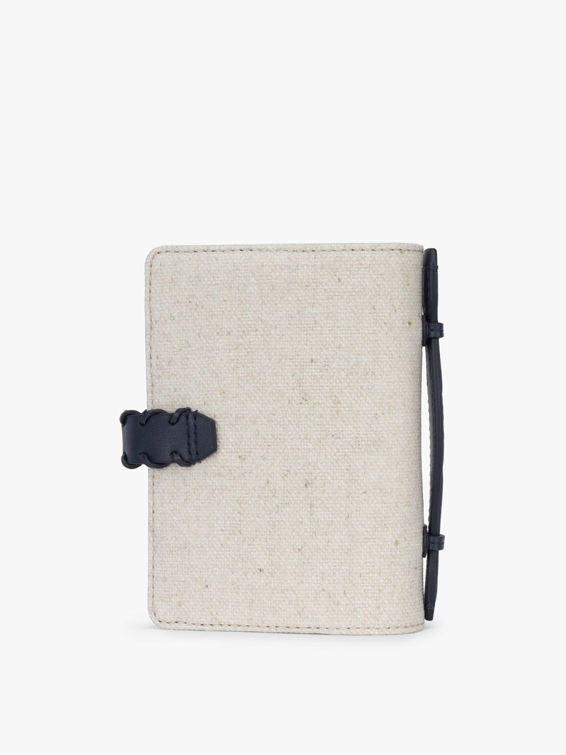 Backside of CALPAK Colette Multi Passport Wallet in beige canvas material and blue finishings in Natural Navy