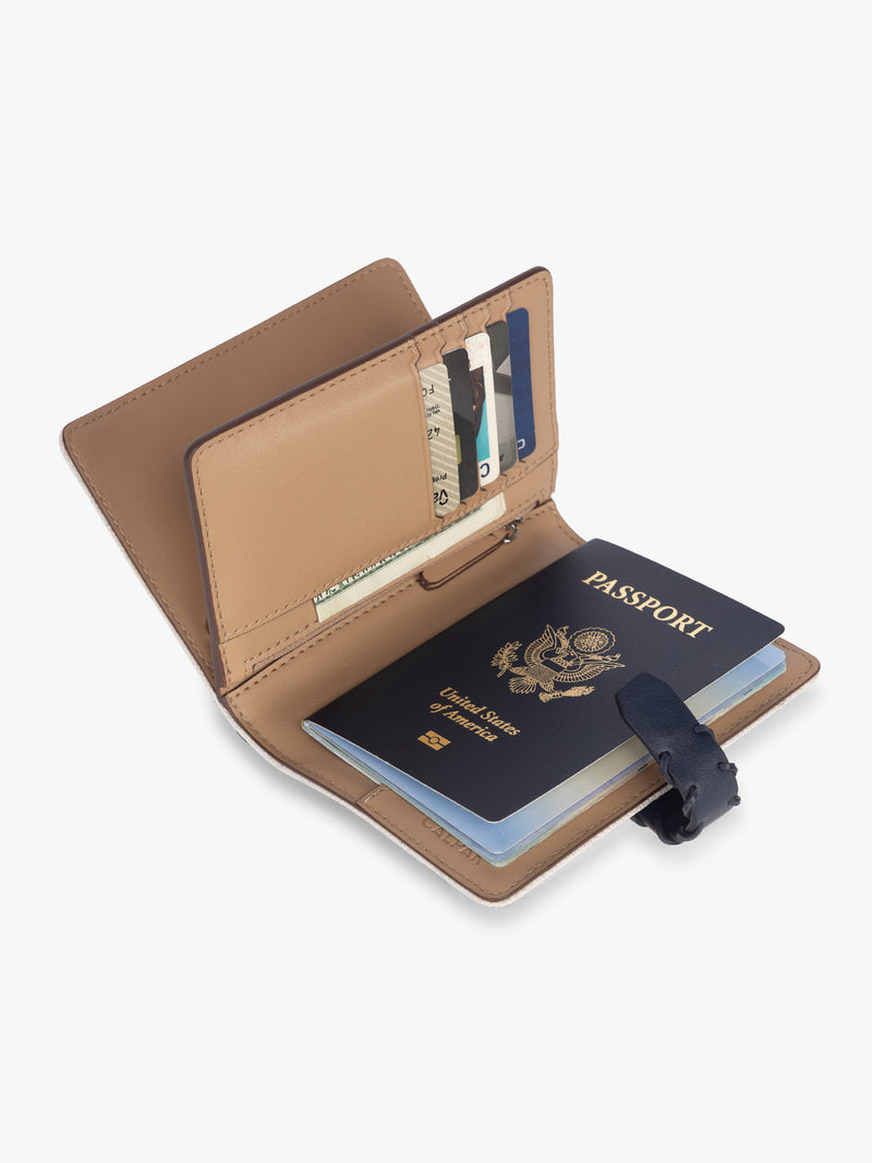 Opened with passport and card slots of CALPAK Colette Multi Passport Wallet in beige canvas material and blue finishings in Natural Navy
