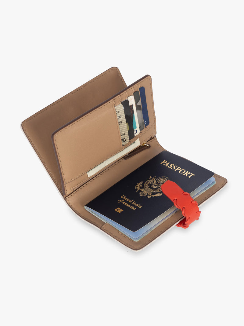 Opened with passport and card slots of CALPAK Colette Multi Passport Wallet in beige canvas material and red finishings in Natural Tomato