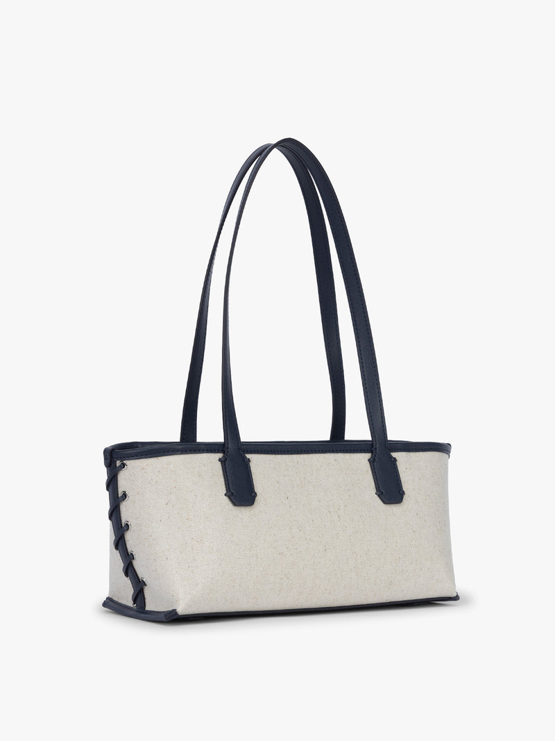 Side view with stitching of CALPAK Colette Canvas Shoulder Tote in beige canvas material  and side stitch in blue finishing