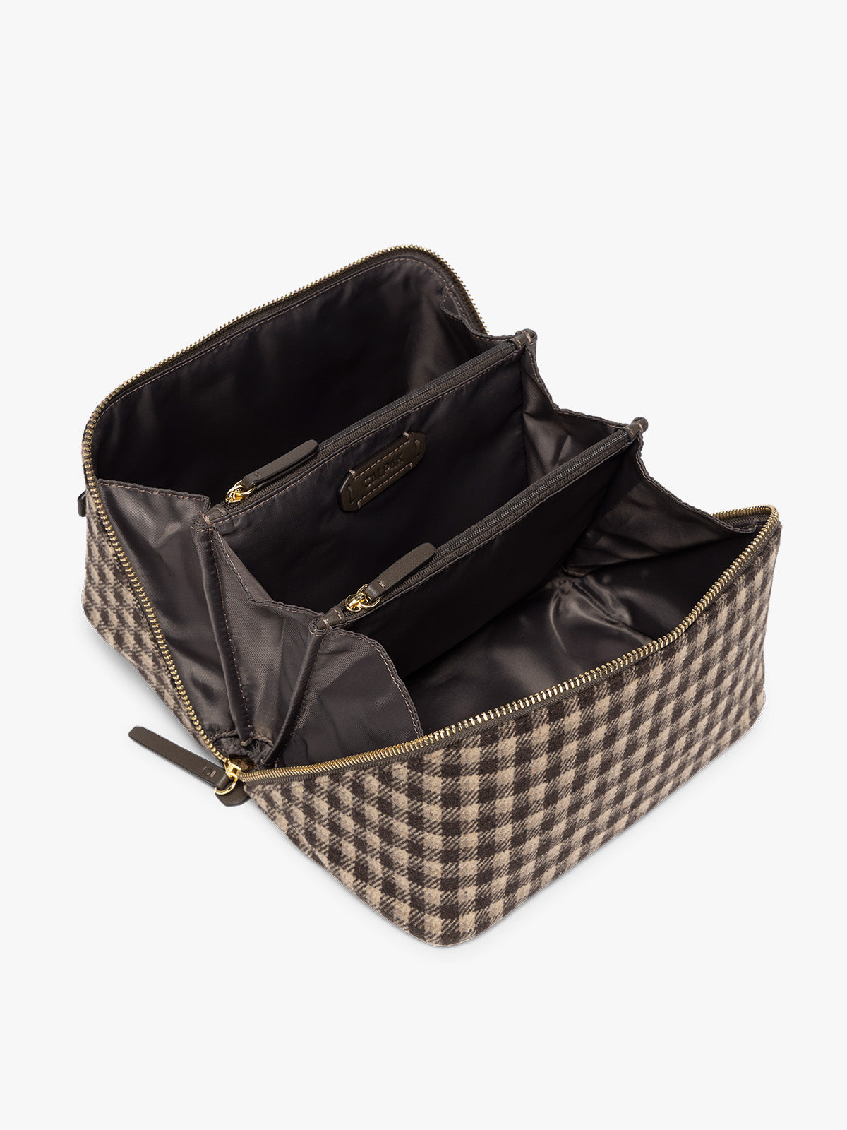 Opened view with compartments and brown lining of the toiletry bag with zipper and top handle in a brown plaid from CALPAK in Mushroom Plaid shown against a grey background; CLTB2601-MUSHROOM-PLAID