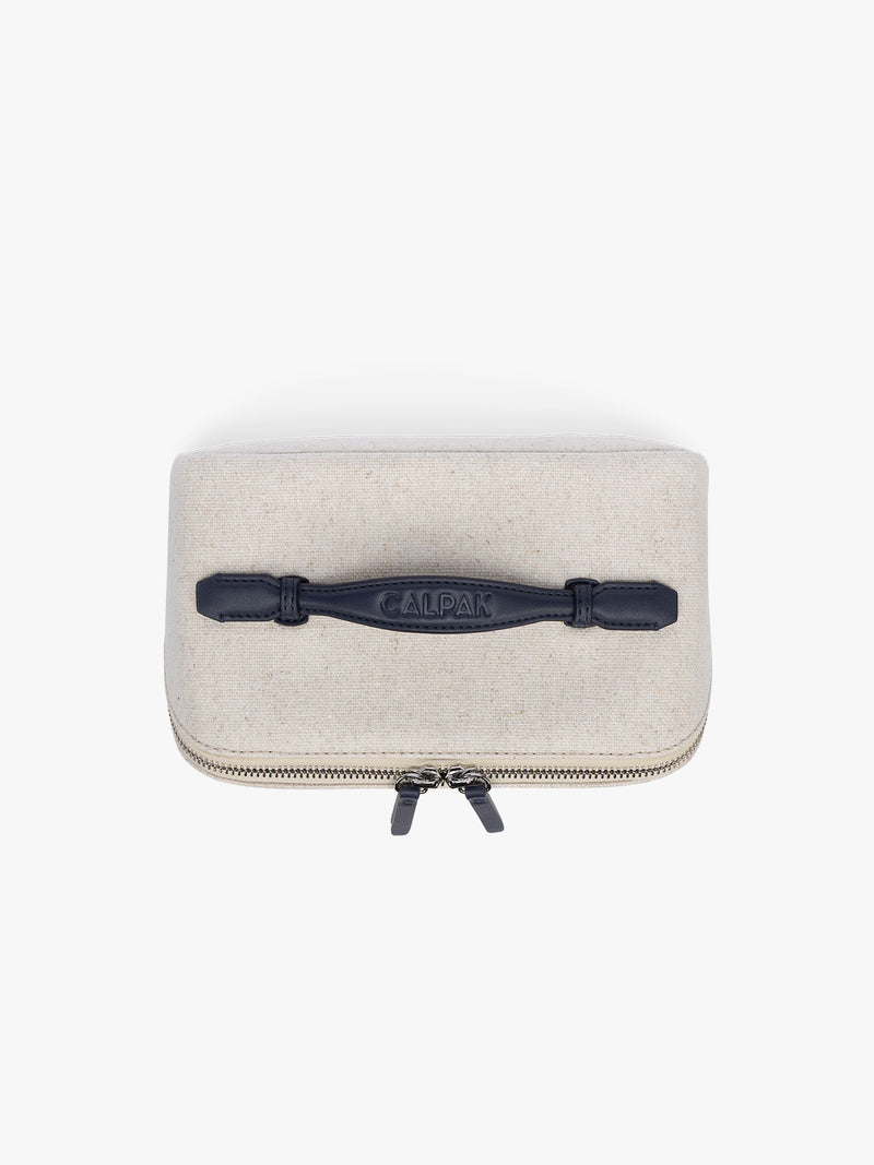 Top view of CALPAK Colette Lay-Flat Canvas Toiletry Bag in beige canvas  material and blue finishing