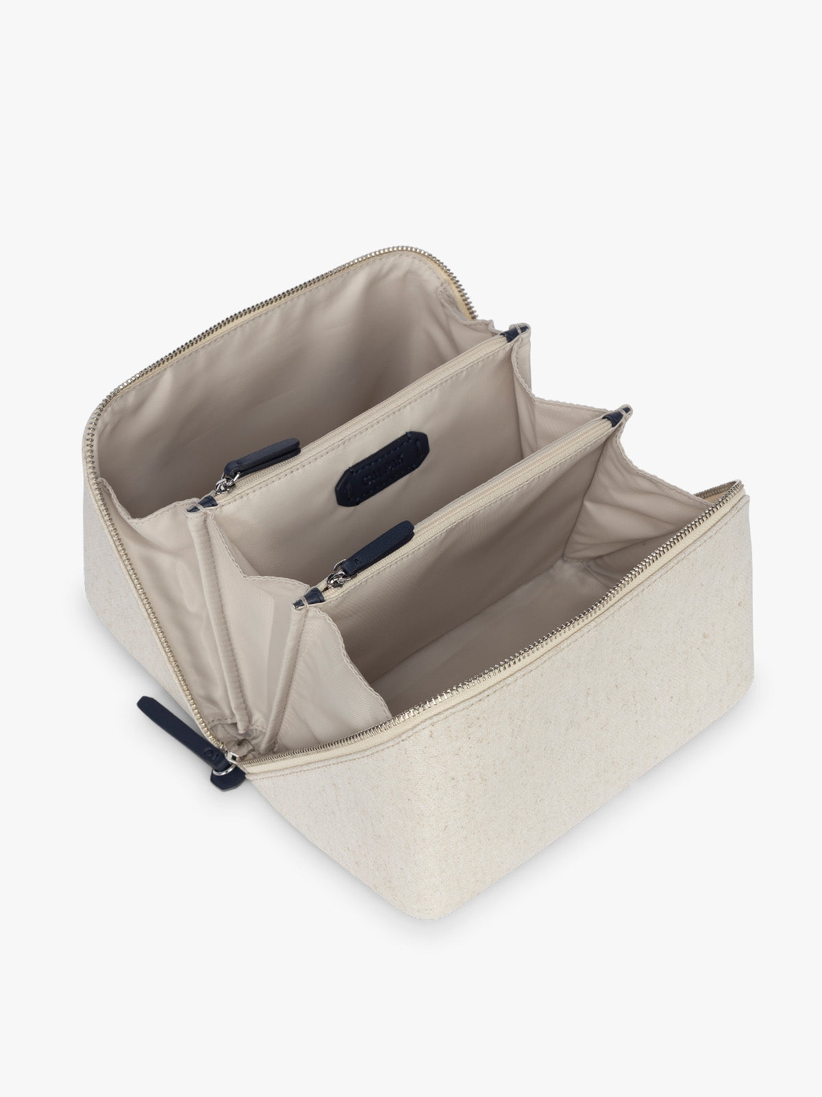Opened CALPAK Colette Lay-Flat Canvas Toiletry Bag in beige canvas  material and blue finishing; CLTB2601-NATURAL-NAVY