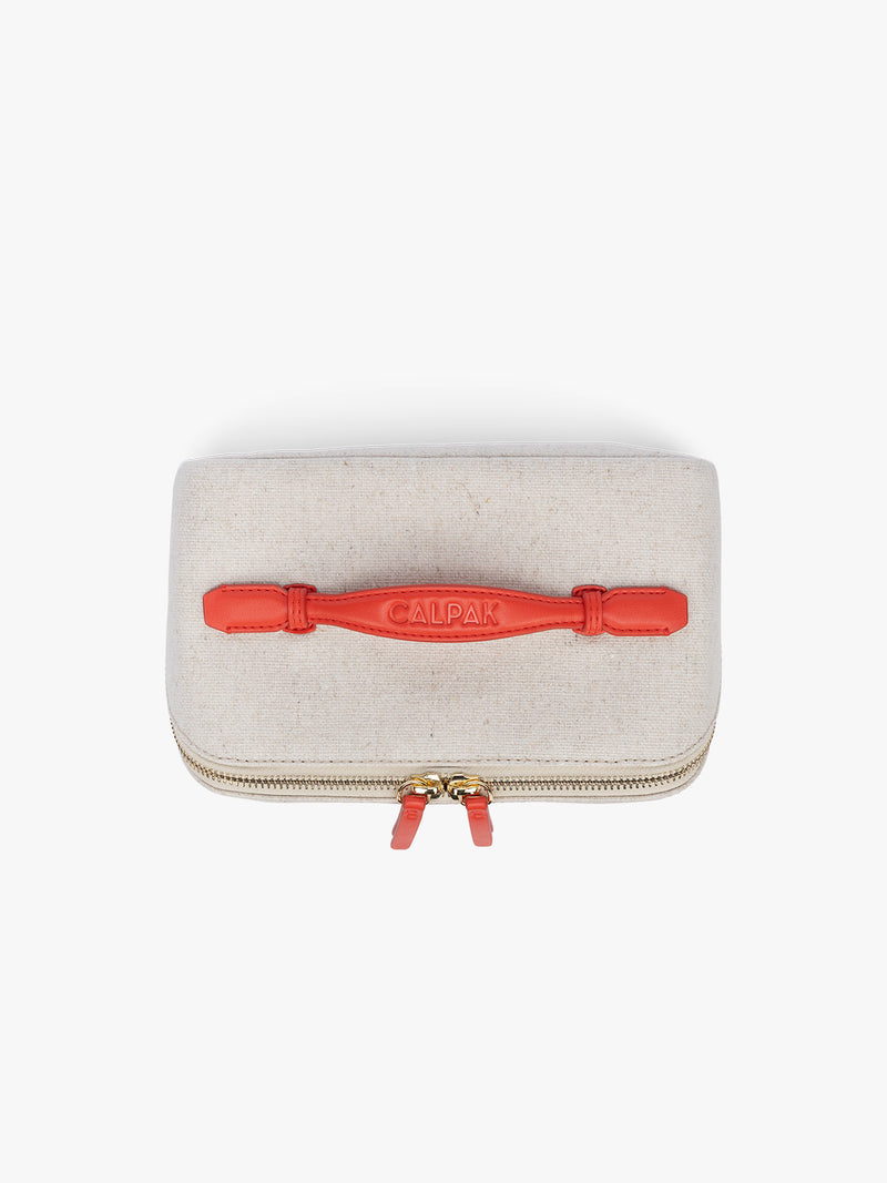 Top handle of CALPAK Colette Lay-Flat Canvas Toiletry Bag in beige canvas  material and red finishing