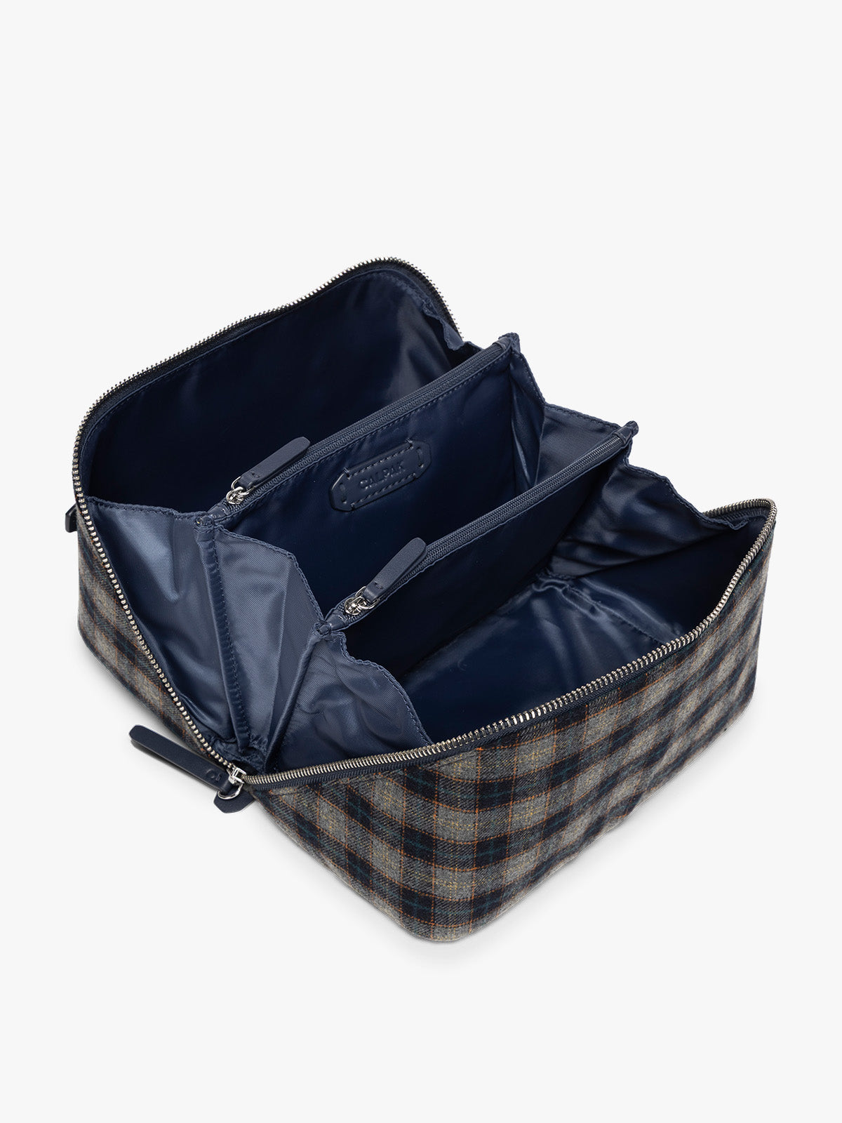 Opened view with compartments and blue lining of the toiletry bag with zipper and top handle in a grey and navy plaid from CALPAK in Navy Plaid shown against a grey background; CLTB2601-NAVY-PLAID