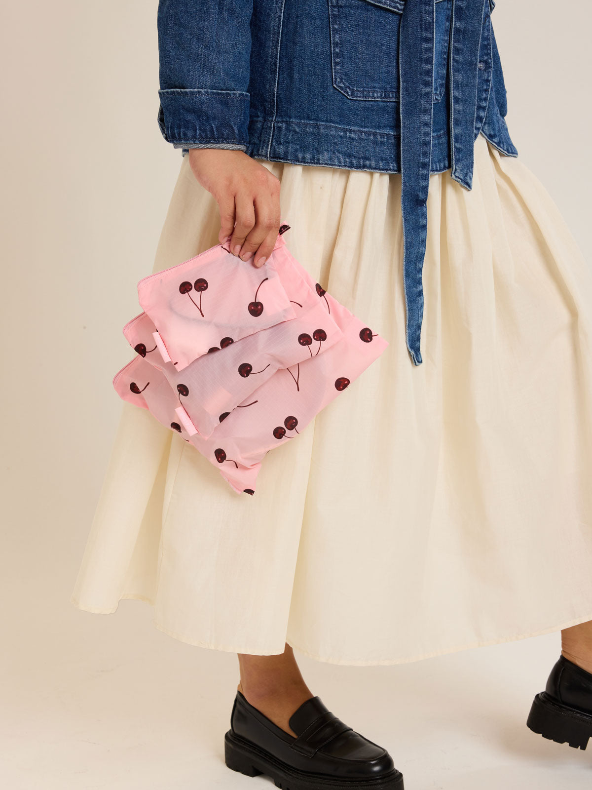 Model holding CALPAK  Compakt Zippered Pouch in pink with cherry pattern; KZB2001-BLOSSOM-CHERRY
