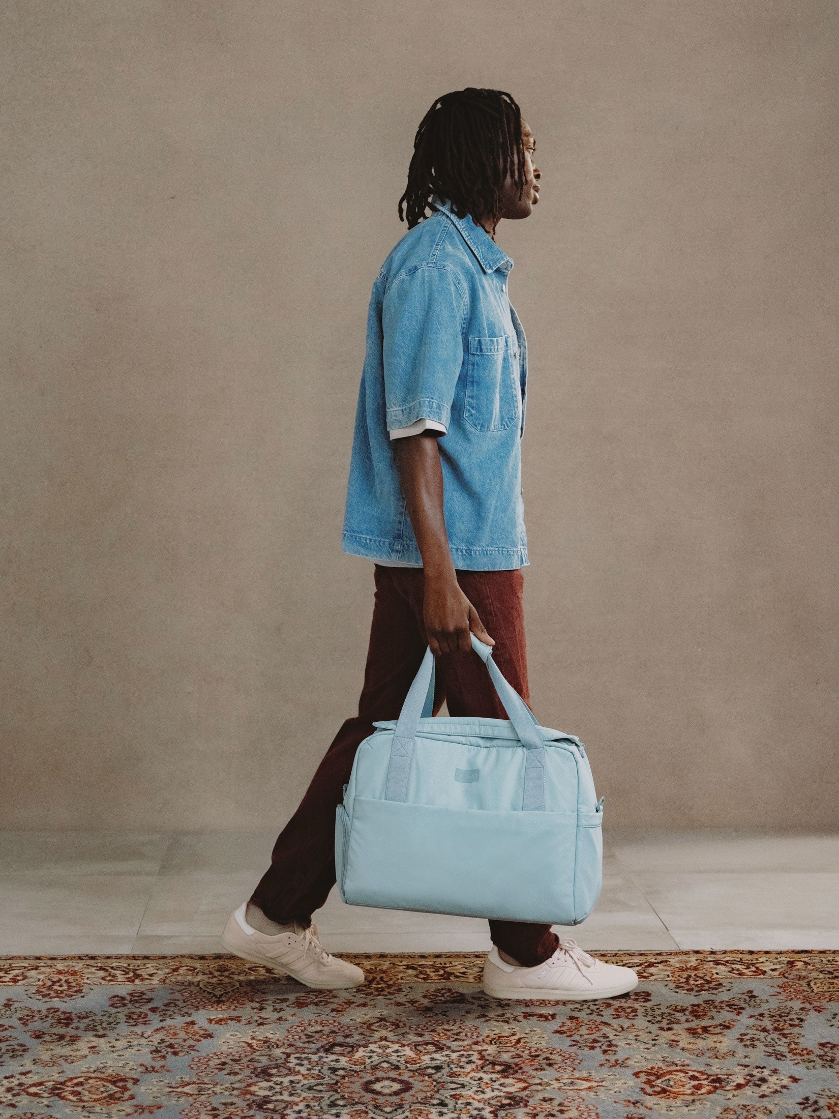 Model holding CALPAK Connect Laptop Duffel by carrying handles in bluebell; DCN2401-BLUEBELL