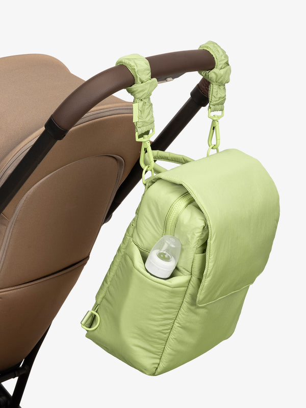 CALPAK Convertible Mini Diaper Backpack attached to stroller by CALPAK Stroller Straps in lime green