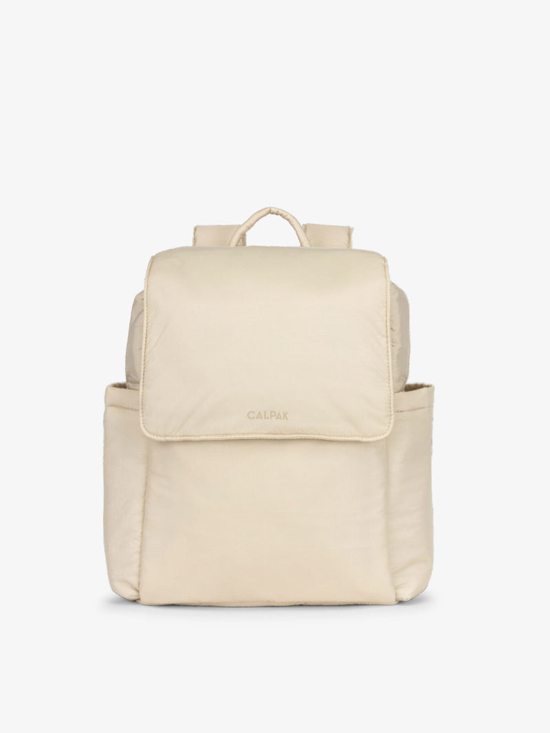 The Convertible Mini Diaper Backpack in oatmeal, featuring a front zippered pocket, top handle, and adjustable straps