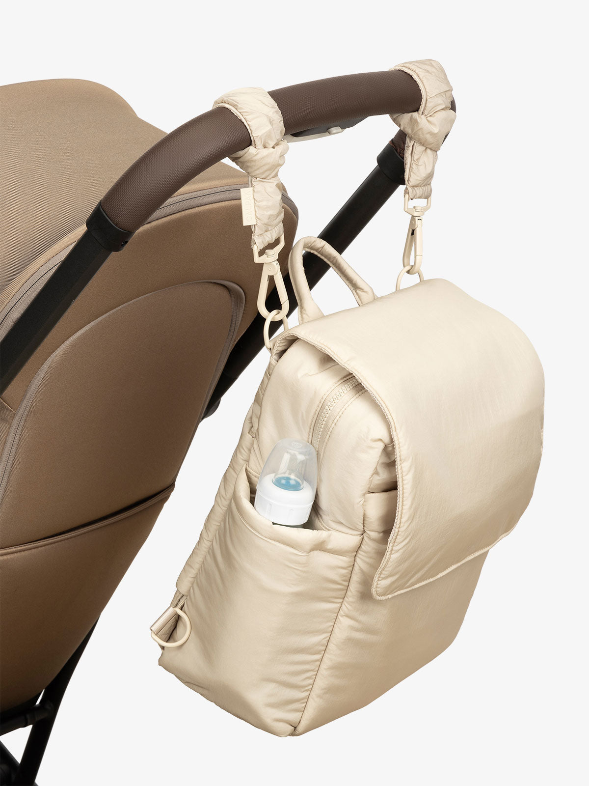 CALPAK Convertible Mini Diaper Backpack attached to stroller by CALPAK Stroller Straps in beige oatmeal; BPC2401-OATMEAL, BBPC2401-OATMEAL