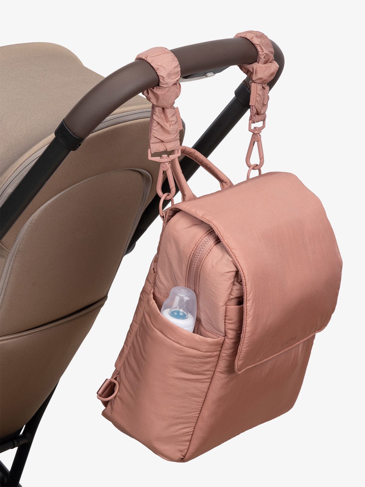 CALPAK Convertible Mini Diaper Backpack attached to stroller by CALPAK Stroller Straps in pink peony