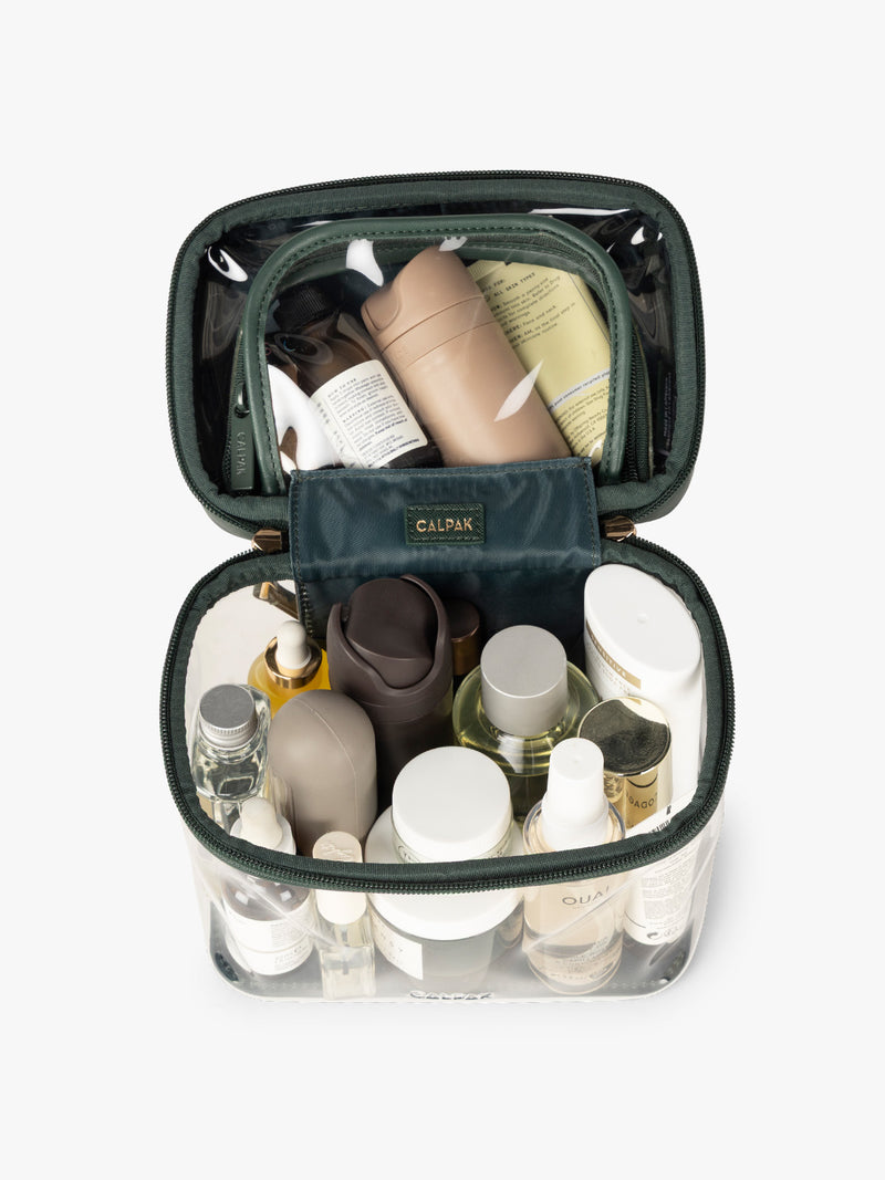 Makeup and toiletries in the CALPAK Clear Train Case in dark green Emerald