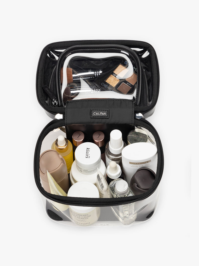 Toiletries and makeup in the Opened and empty CALPAK Clear Train Case in Glazed Black