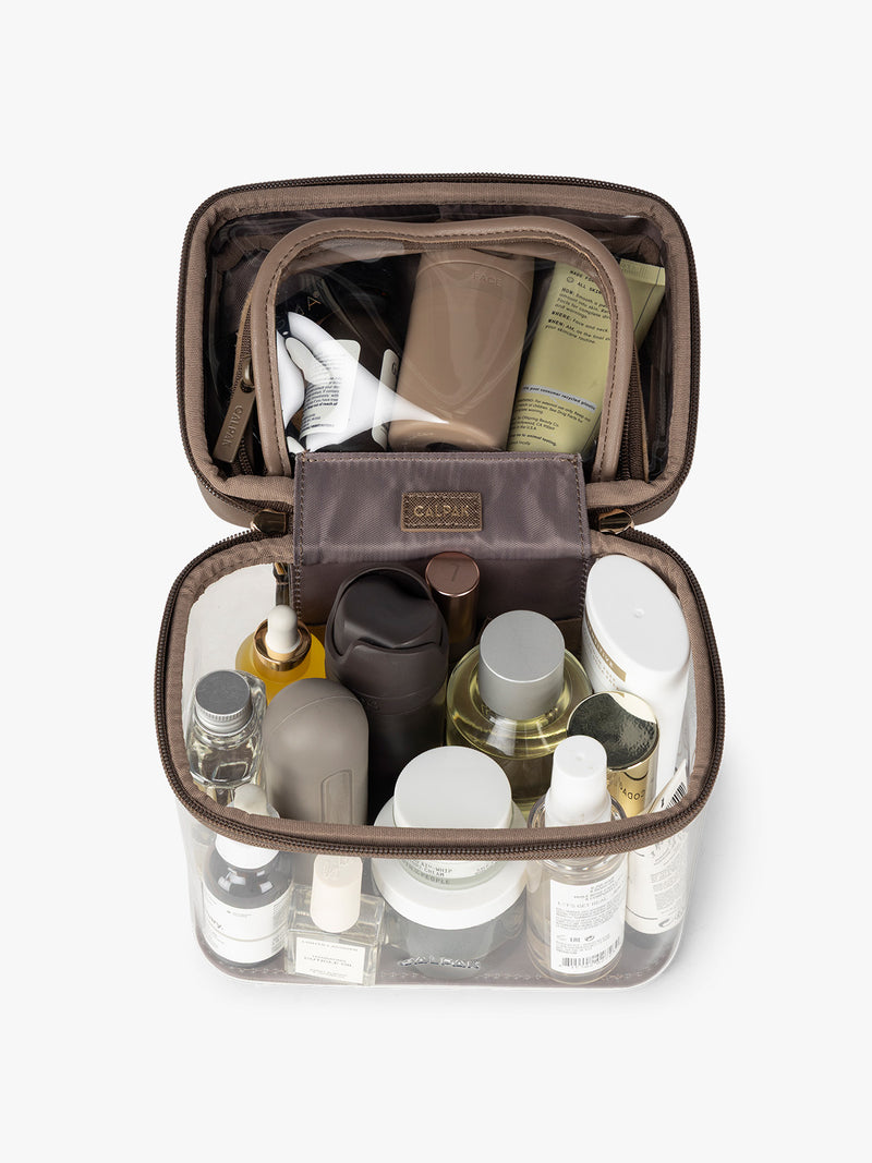 Makeup and toiletries in the CALPAK Clear Train Case in brown Mocha
