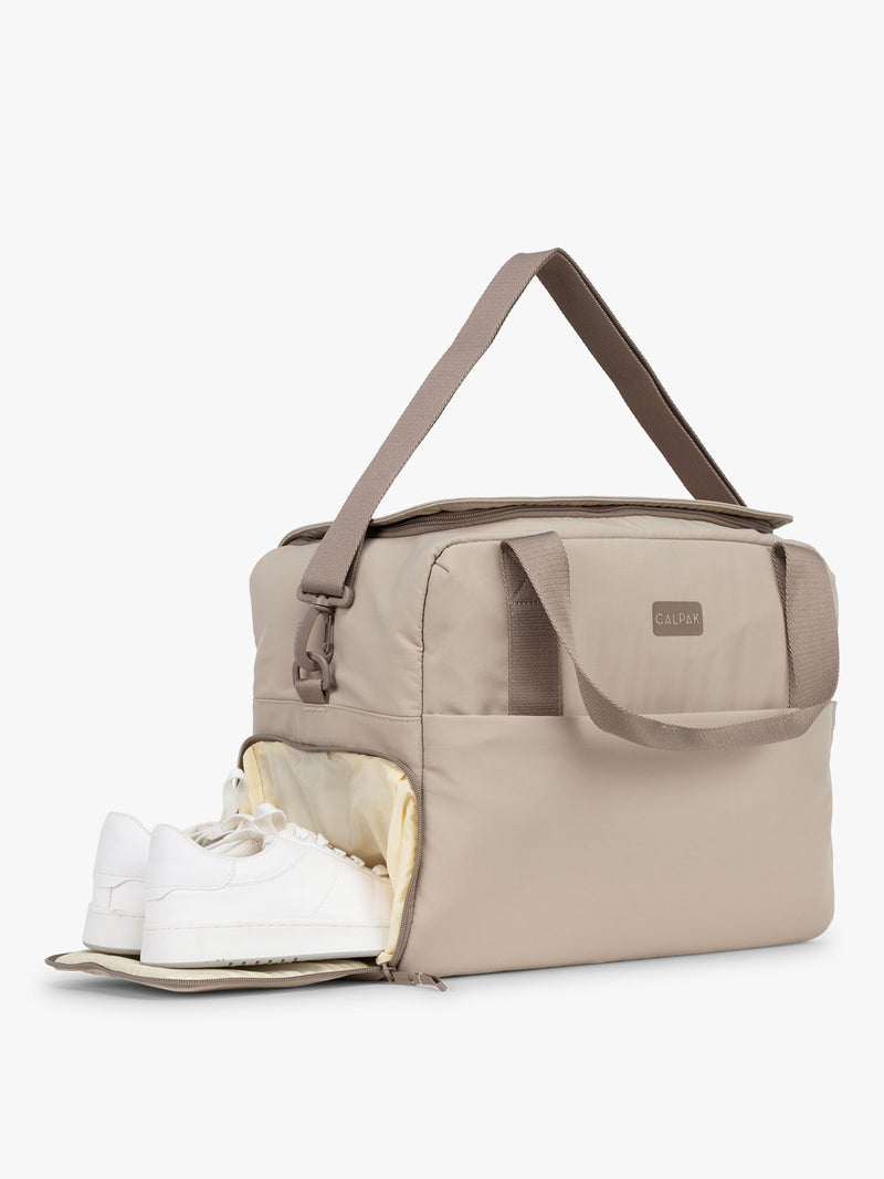 CALPAK Laptop Duffel in beige Greige side view with shoe comparment on white background