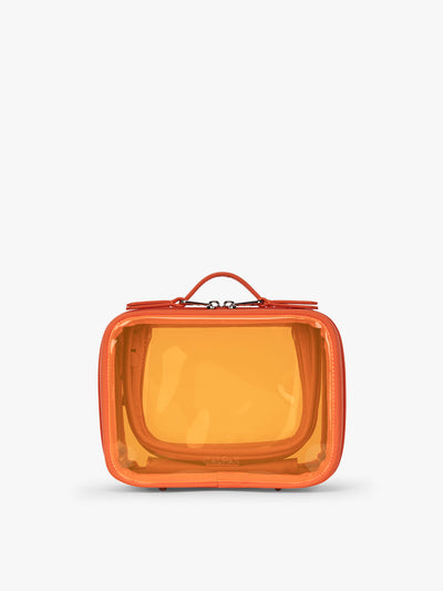 CALPAK x Dedcool Collaboration of the Small Clear Cosmetic Case in orange Papaya with toiletry items and perfumes  on a airport chair; CCM2001-DEDCOOL view 1