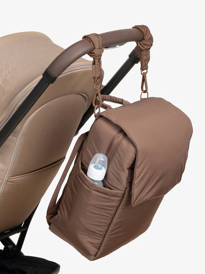 CALPAK Diaper Tote Bag in brown Hazelnut with brown Hazelnut Stroller Straps attached to a black stroller; BTBB2401-HAZELNUT-HAZELNUT view 2