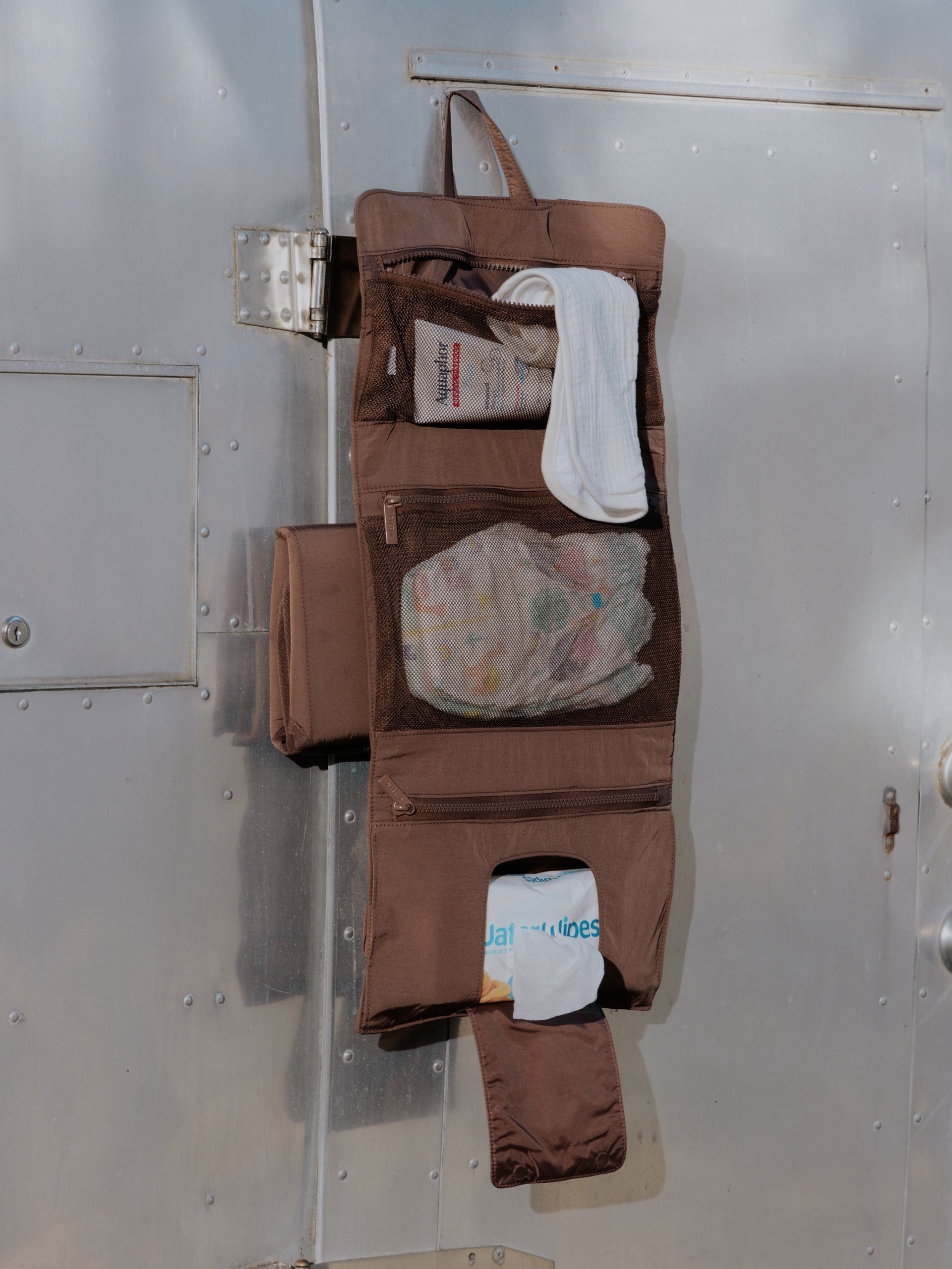 Hazelnut brown CALPAK diaper changing pad organizer with collapsible hanging hook, mesh interior pockets and a designated wipe pocket; 
CPB2402-HAZELNUT