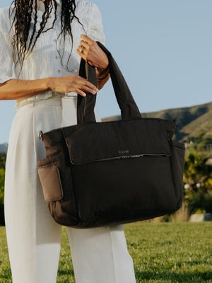 Model displaying CALPAK Diaper Tote Bag with Laptop Sleeve in black; TBB2401-BLACK