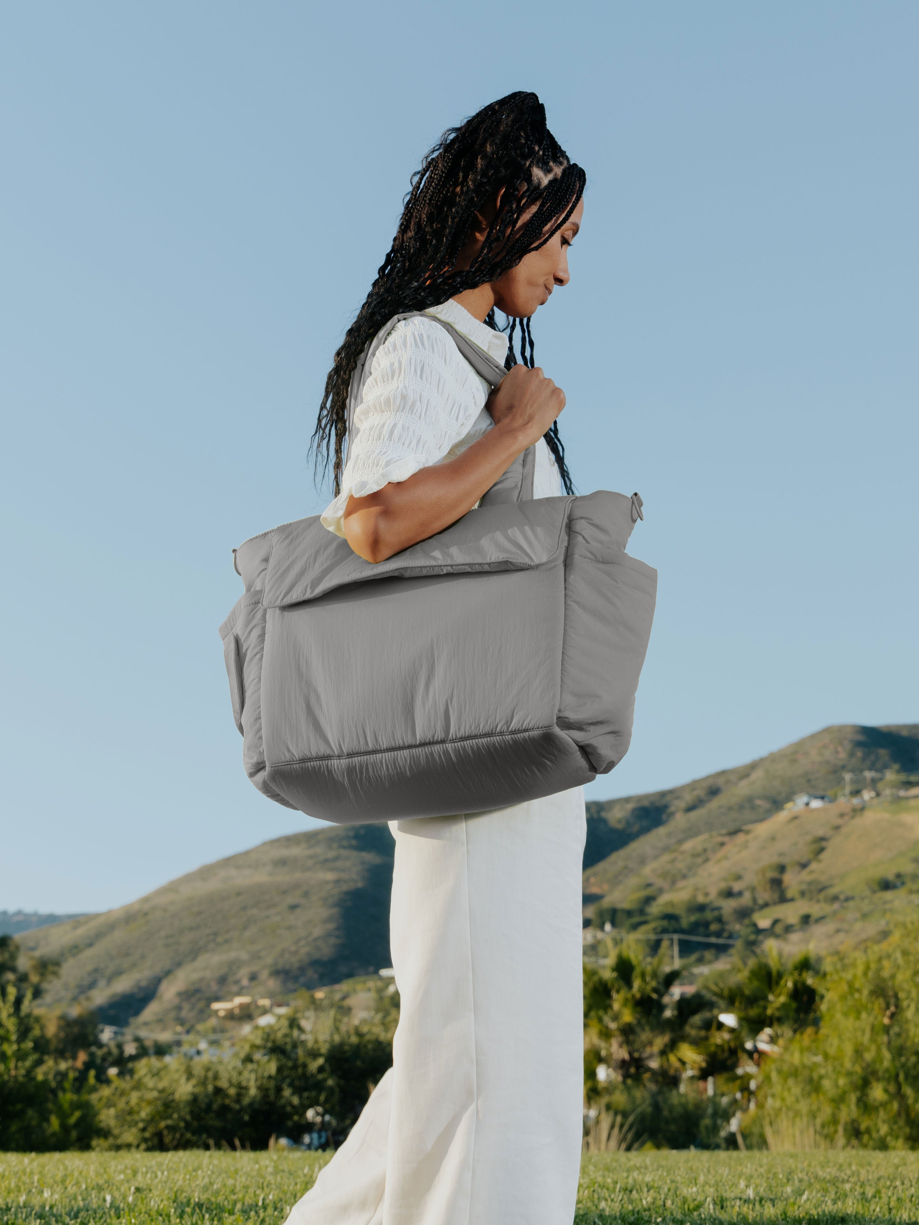 Model wearing slate gray CALPAK Diaper Tote Bag with Laptop Sleeve over shoulder