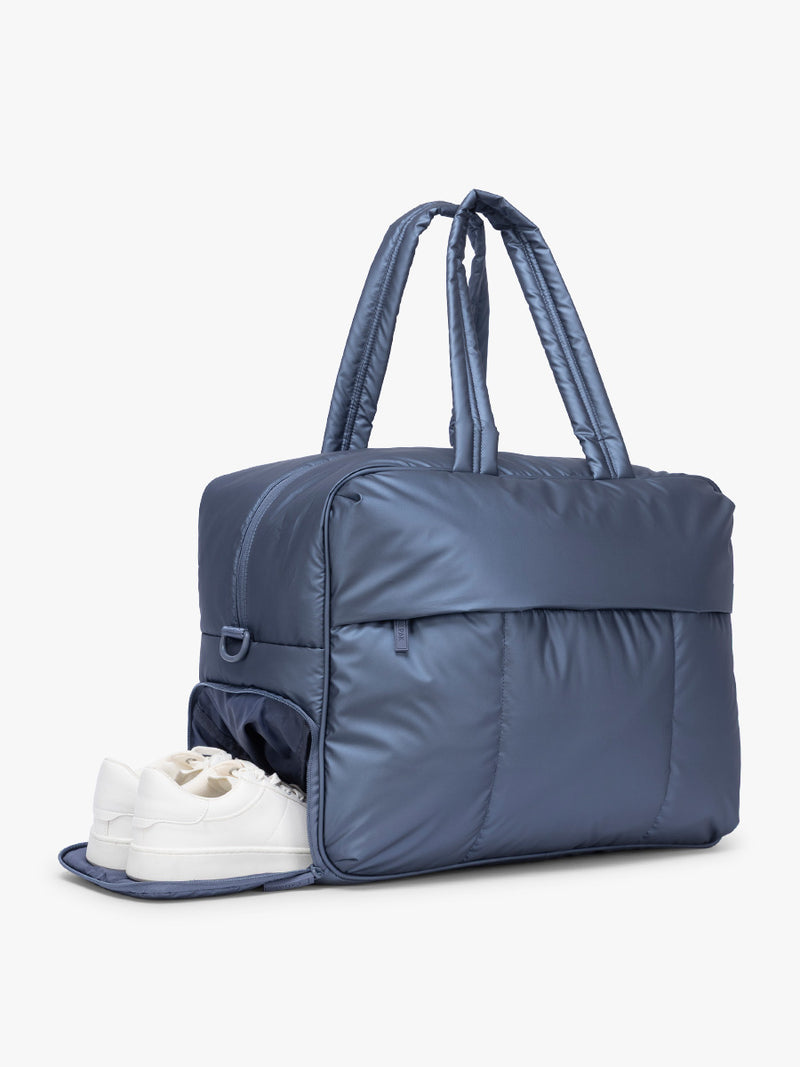 Shoe compartment of  CALPAK Luka Large Duffel in dark blue metallic material in Metallic Indigo