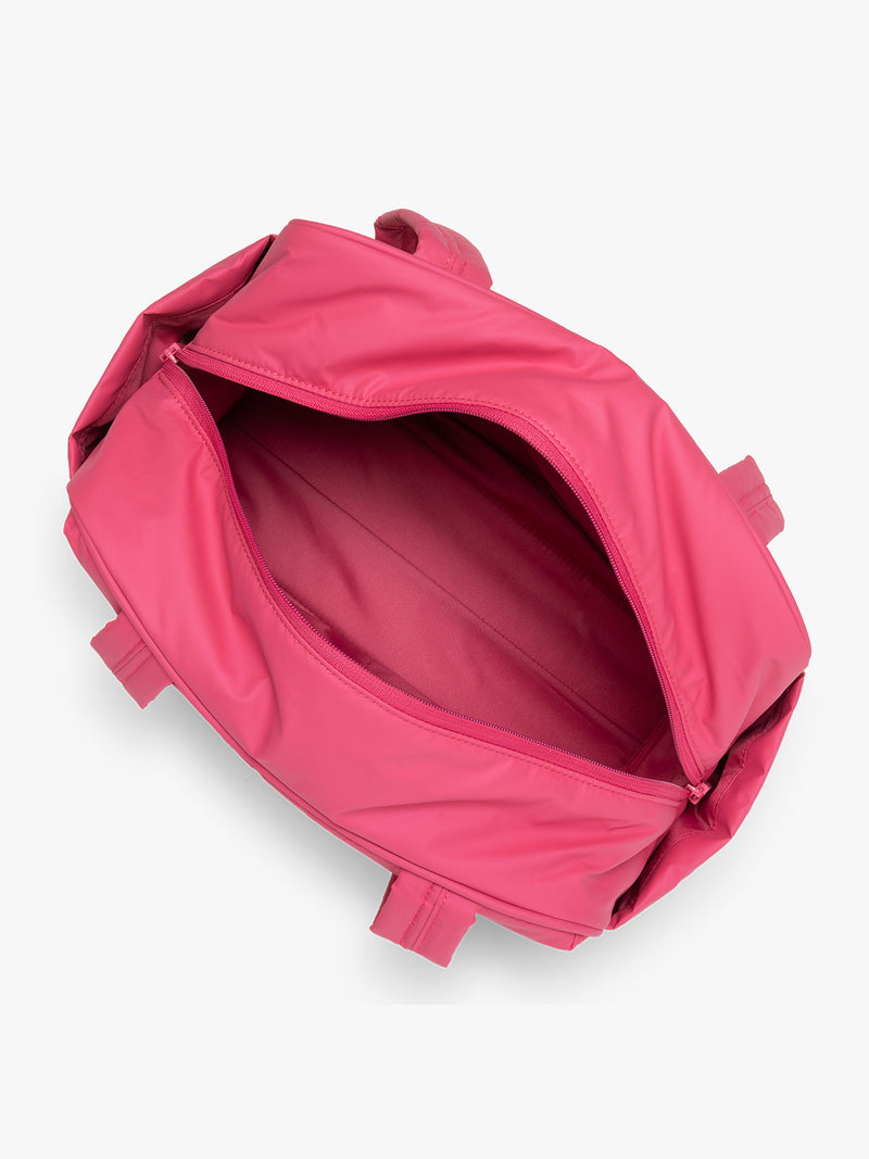 Opened interior of CALPAK Luka Mini Duffel in bright pink on a white background