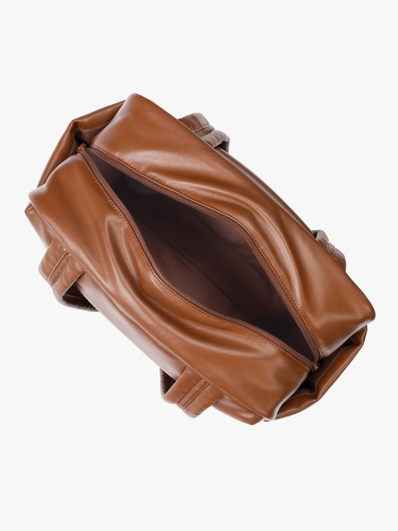 Top zipper view of Honey brown vegan leather CALPAK Luka Mini Duffel with dual top handles and side pockets, photographed against a clean white background
