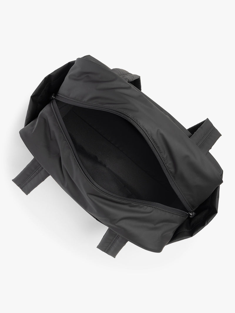 CALPAK Mini Duffel in black open interior with puffy exterior, interior and exterior pockets, and padded shoulder straps