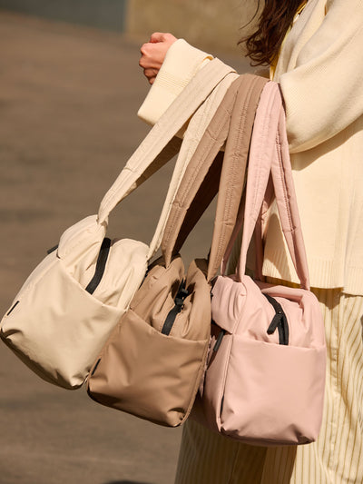 CALPAK Mini Duffel in white Oatmeal front view with puffy exterior, interior and exterior pockets, and padded shoulder straps; DLM2501-OATMEAL view 2