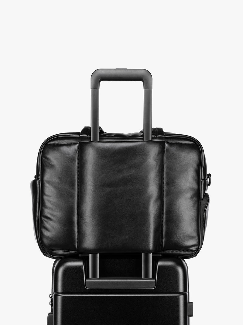 Luggage trolley sleeve of the Black CALPAK Luka Duffel in vegan leather with dual top handles and a front zippered pocket, photographed against a clean white background