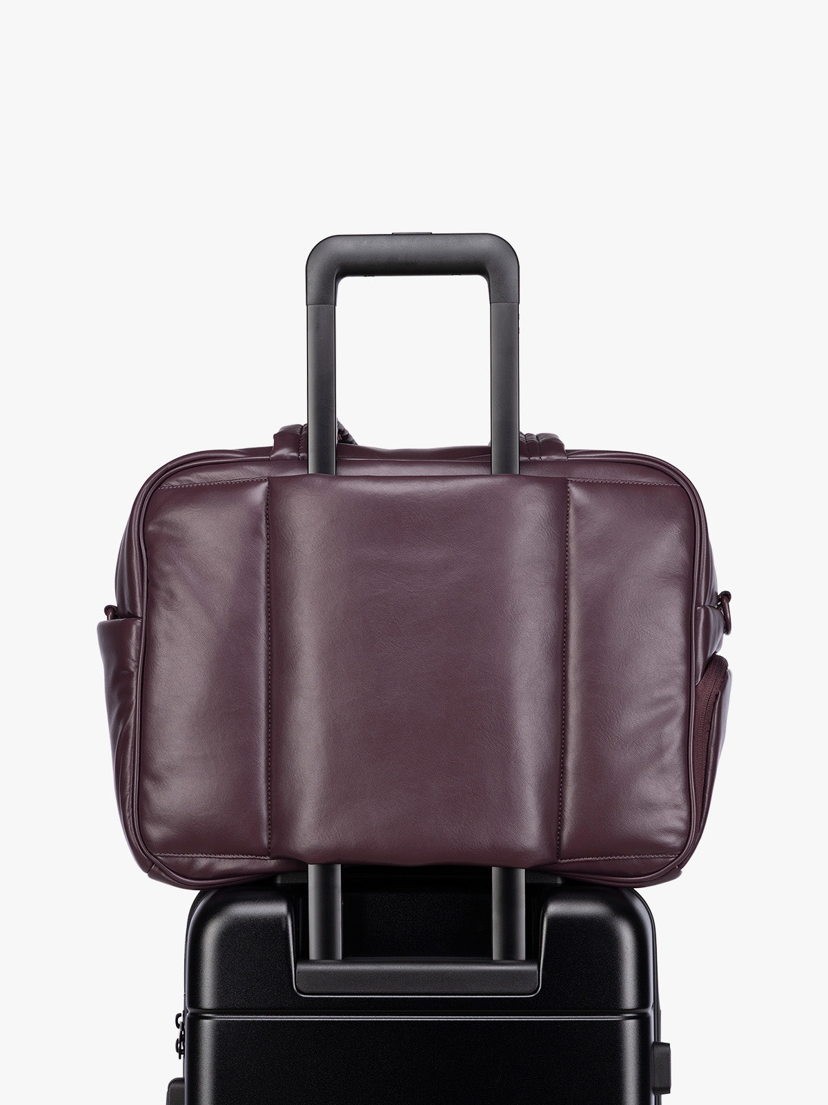 Luggage trolley sleeve of a dark burgundy CALPAK Luka Duffel in vegan leather with dual top handles and a front zippered pocket, photographed against a clean white background; DSM1901-DARK-CHERRY-PU