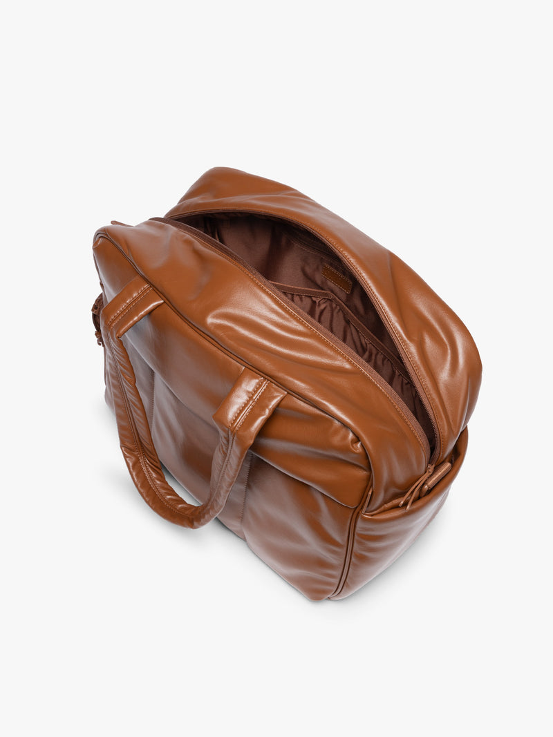 Top view with zipper open showing the inside of Honey Brown CALPAK Luka Duffel in vegan leather with dual top handles and a front zippered pocket, photographed against a clean white background