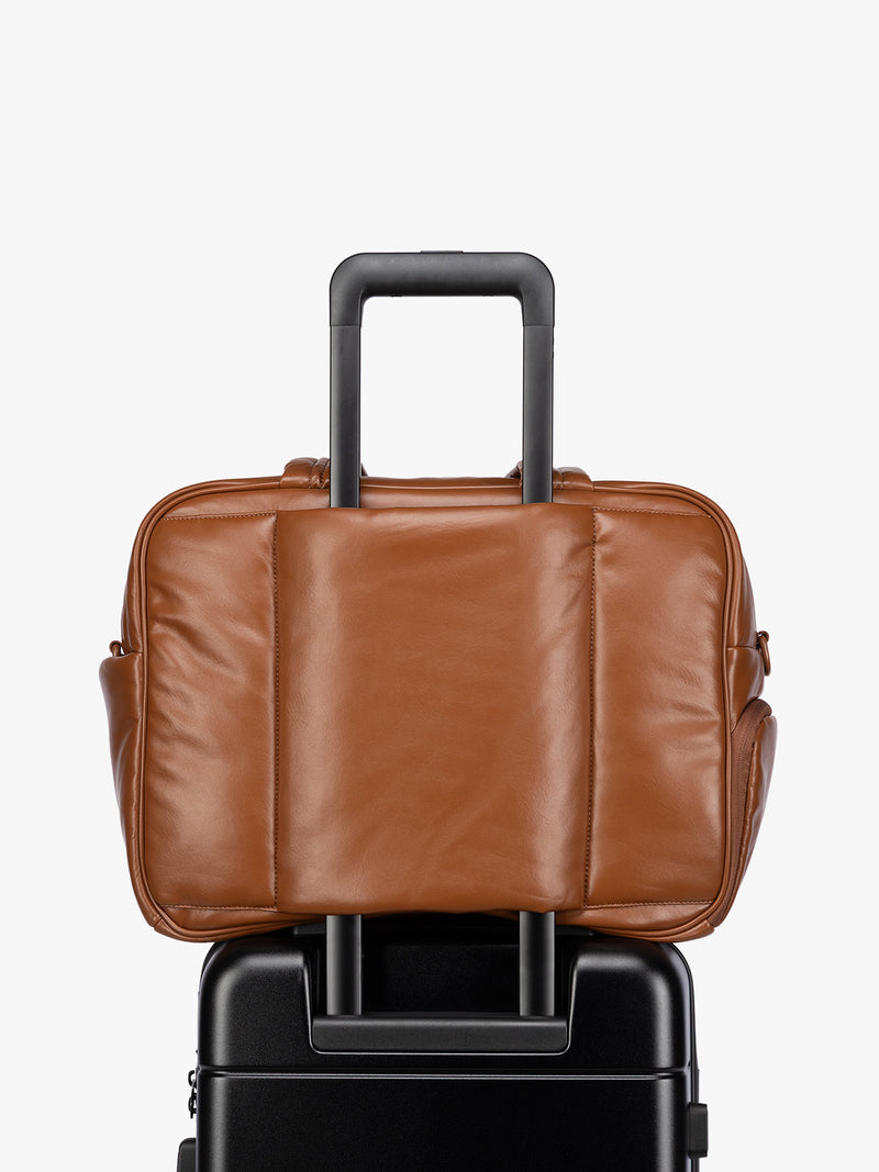 Luggage trolley sleeve of Honey Brown CALPAK Luka Duffel in vegan leather with dual top handles and a front zippered pocket, photographed against a clean white background