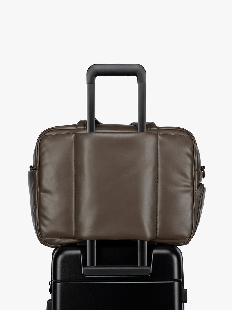 Luggage trolley sleeve of the A dark brown Mushroom CALPAK Luka Duffel in vegan leather with dual top handles and a front zippered pocket, photographed against a clean white background