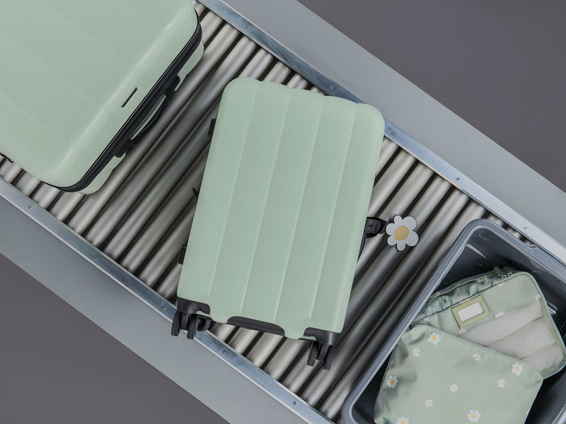 CALPAK Evry Carry On Luggage in mint-green Daisy color at the airport