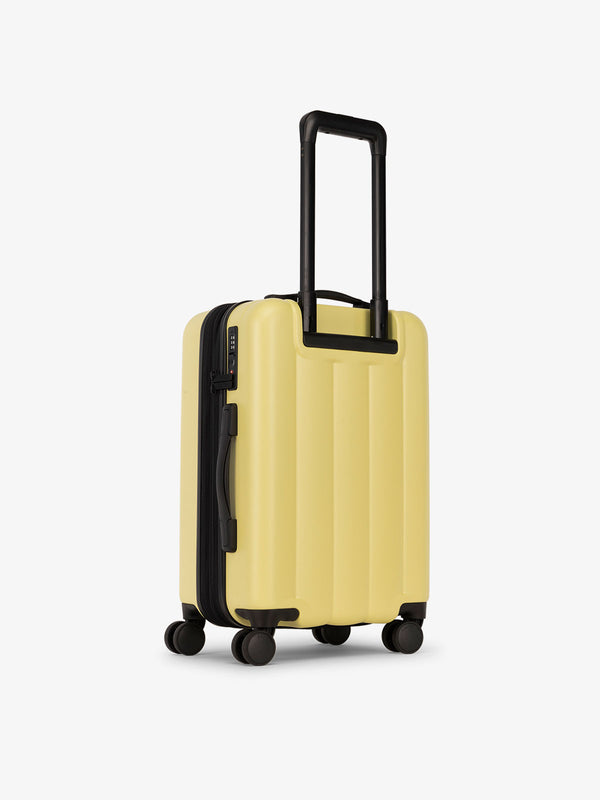 CALPAK carry-on luggage featuring dual spinner wheels and bottom grab handle in yellow