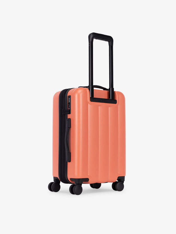 CALPAK carry-on luggage featuring dual spinner wheels and bottom grab handle in orange