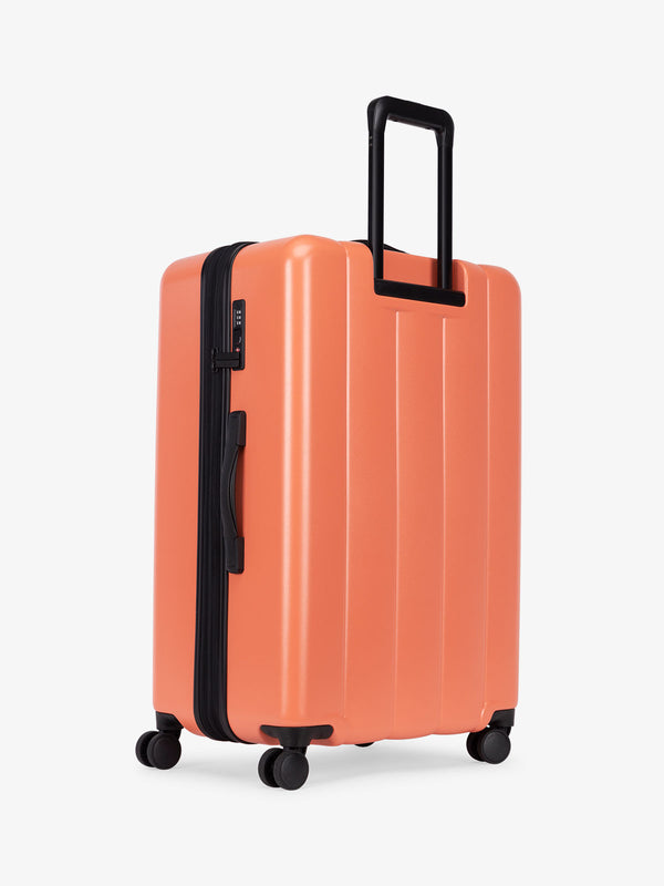 CALPAK large luggage featuring dual spinner wheels and bottom grab handle in persimmon orange