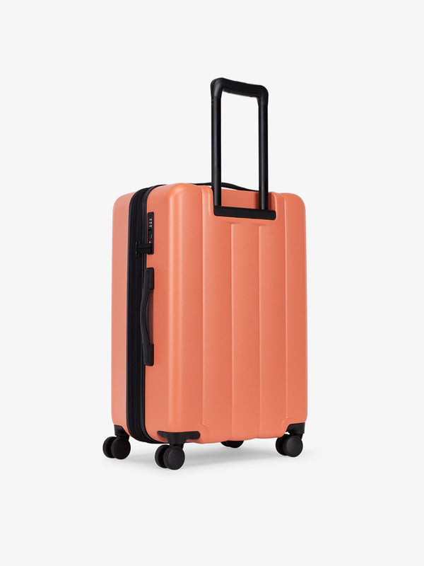 CALPAK medium luggage featuring dual spinner wheels and bottom grab handle in orange