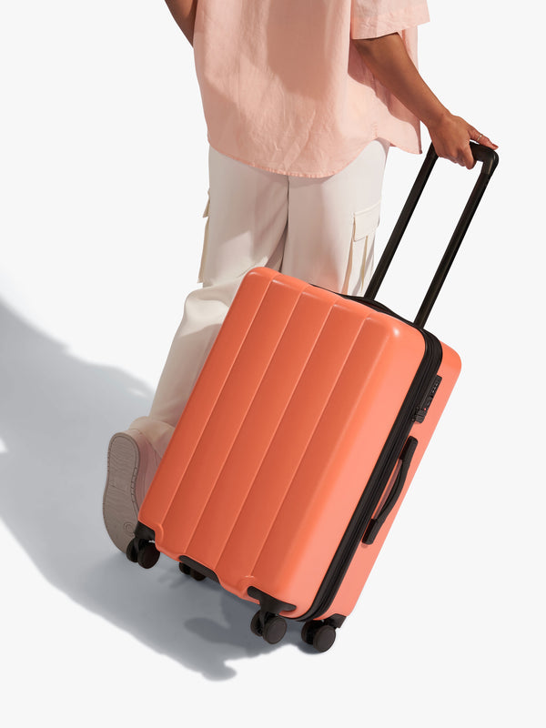 Model rolling CALPAK Evry Medium Luggage in orange persimmon