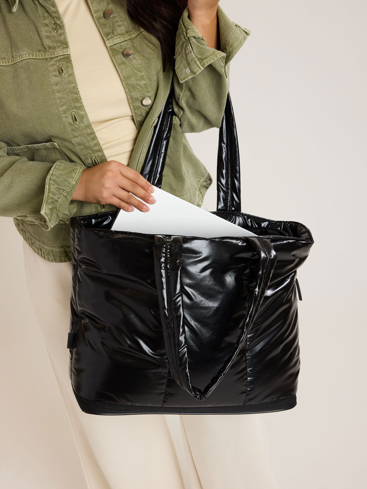 Model putting laptop into CALPAK Luka Expandable Tote in Glazed Black; ALT2201-GLAZED-BLACK